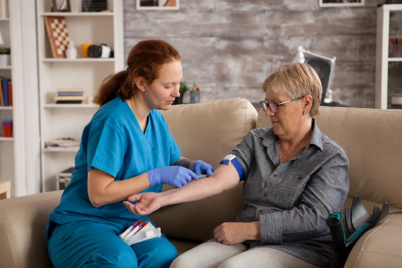 Phlebotomist performing a home blood draw for a senior patient
